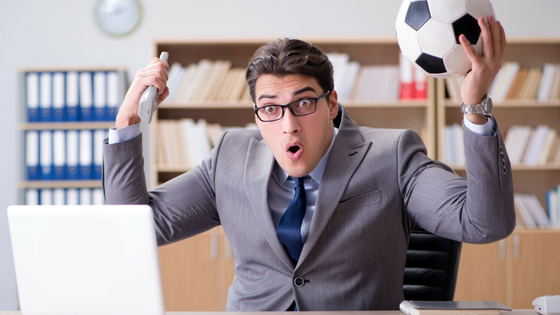 man-cheering-in-business-suit-holding-soccer-ball-while-at-work