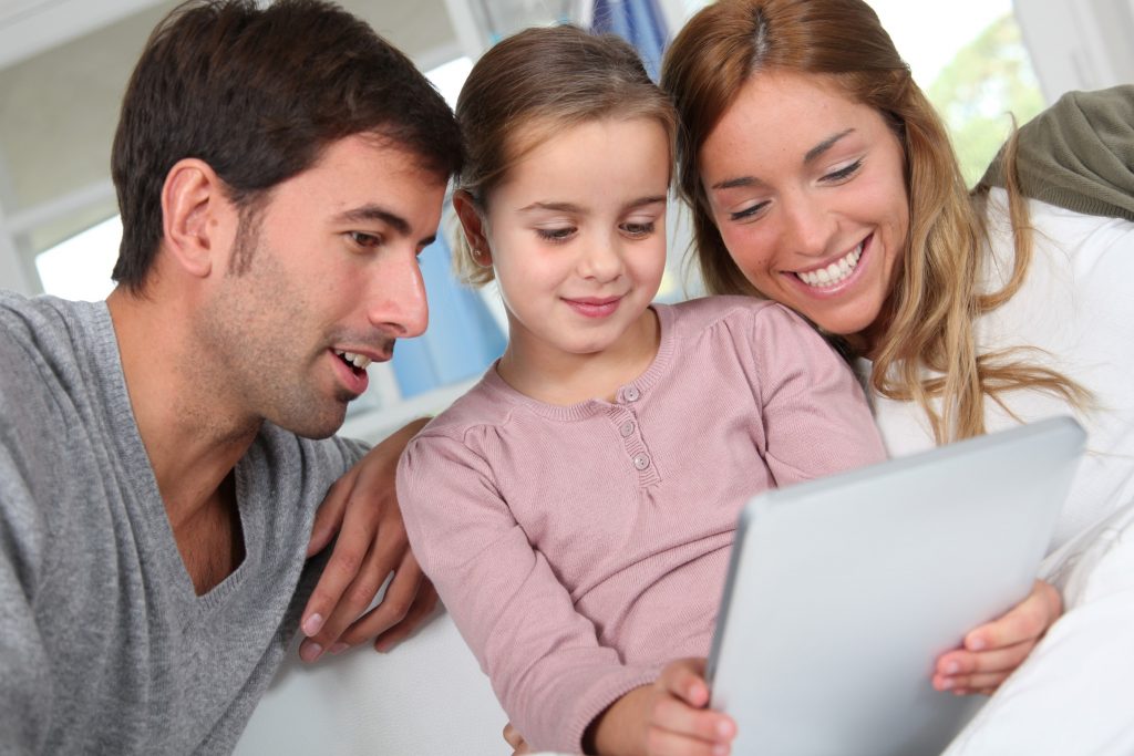 child-holding-tablet-while-mom-and-dad-watch